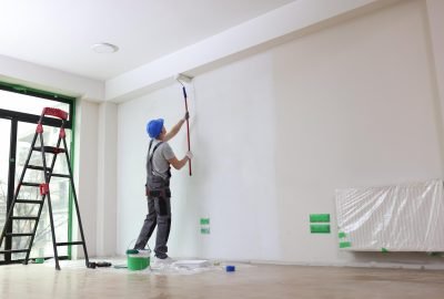 Male painter paints house wall with roller brush. Decoration and improvement interior concept.