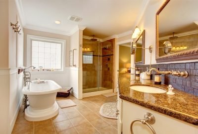 Luxury bathroom interior. Room has glass door shower cabinet with granite top ans two sinks mirrors and white bath tub